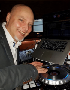 DJ Chris lachend vor DJ Pult